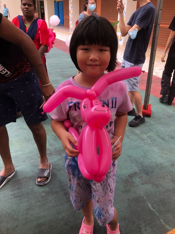 Girl holding a pink balloon dog at a party