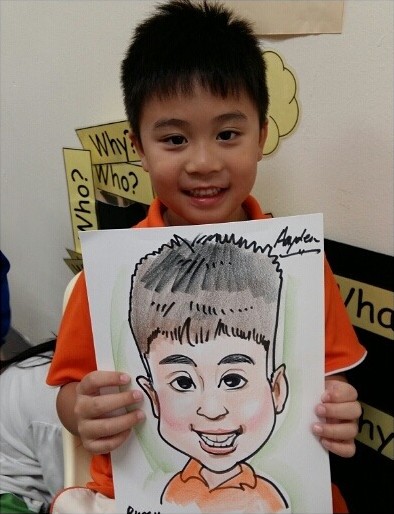 Boy holding up the caricature drawn of him at his party