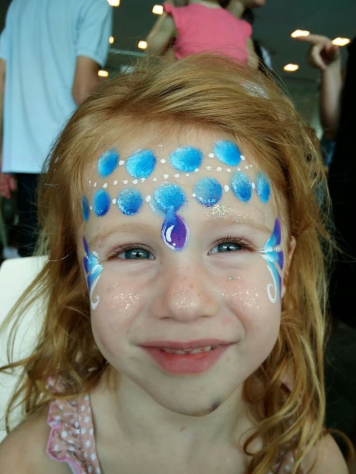 Girl smiling with a blue butterfly design painted across her face