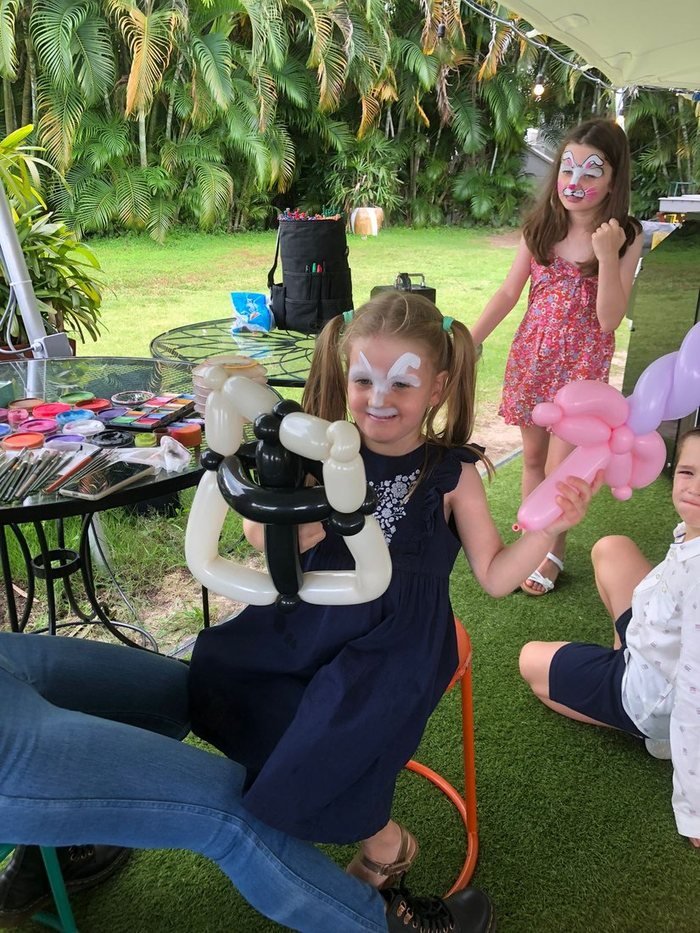 Girl with butterfly face paint holding a balloon