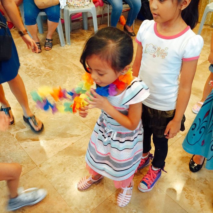 Children mid-game at a party, passing a colourful garland