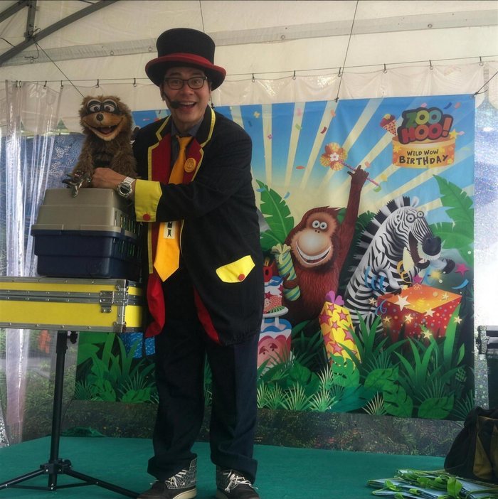 Magician in a top hat performing with a puppet at a children's party